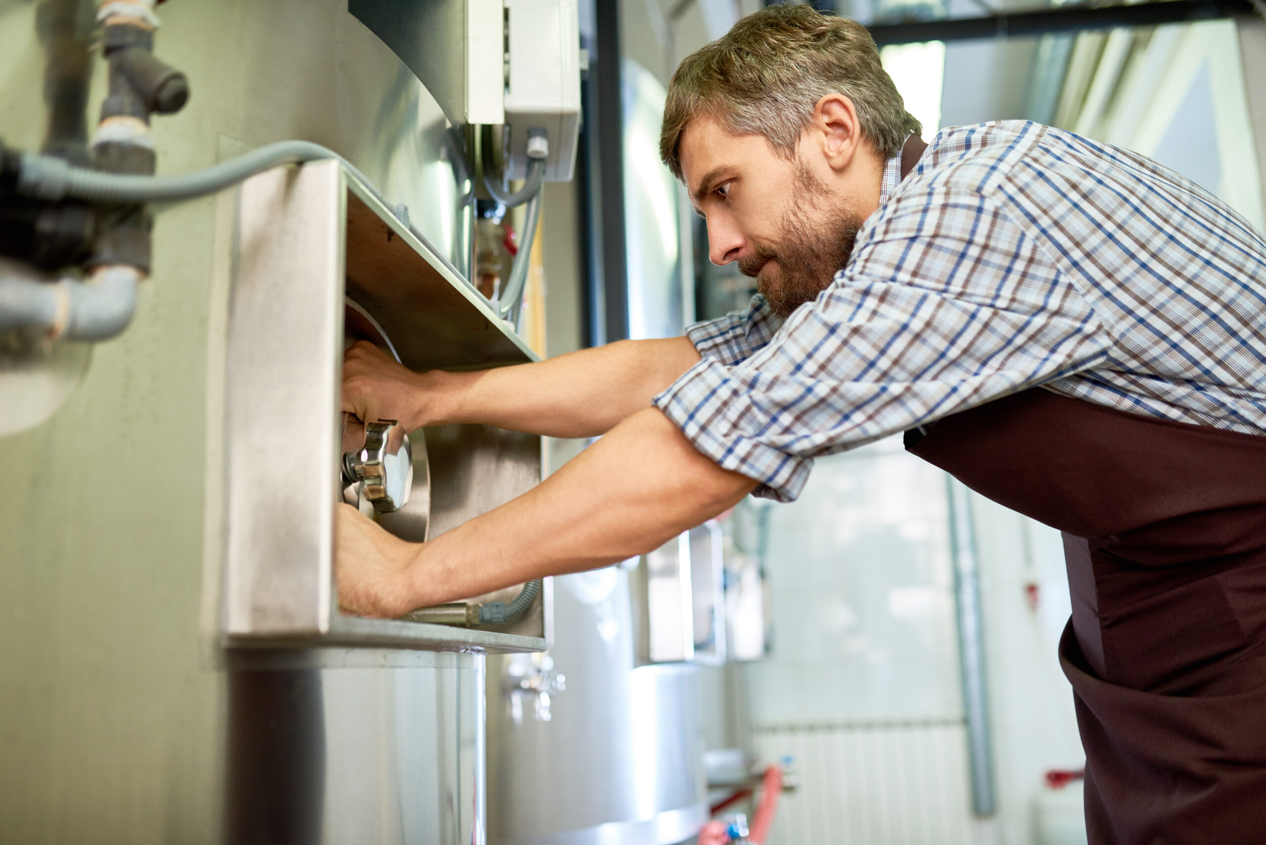 Busy skilled maintenance technician repairing brewery equipment