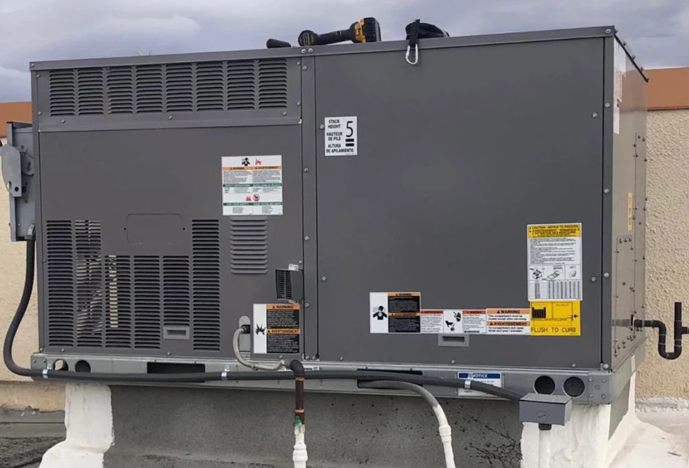 Exterior view of a large industrial generator on a concrete pad with piping and warning labels.
